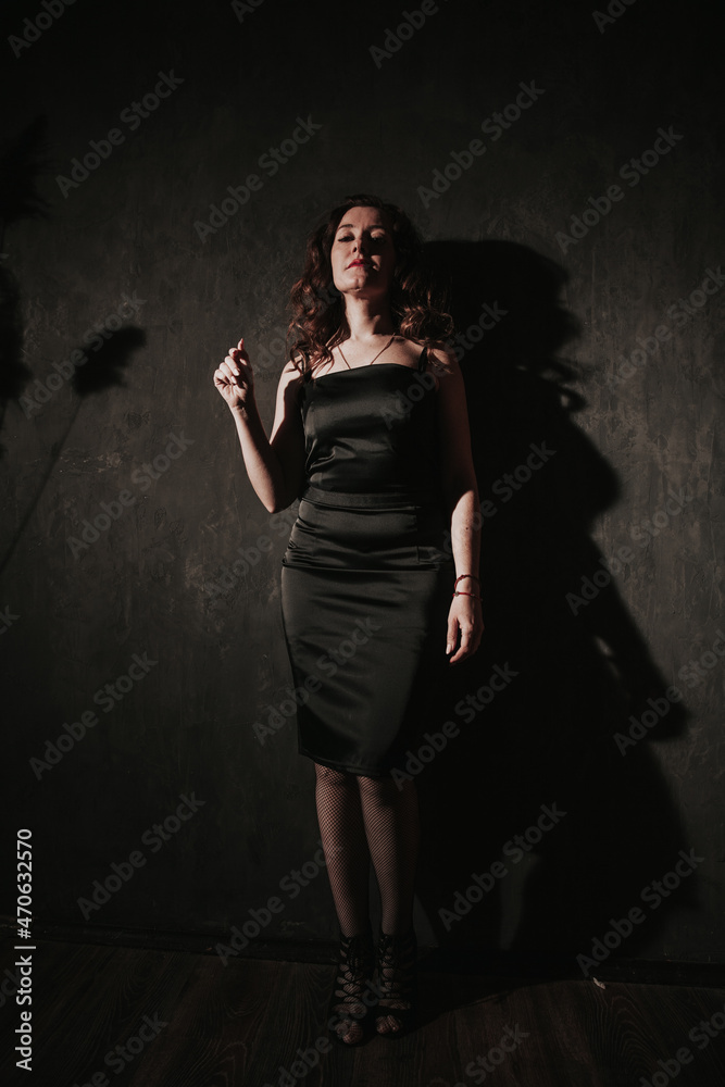 portrait of a beautiful brunette woman in a black dress in the dark portrait of a beautiful brunette woman in a black dress in the dark
