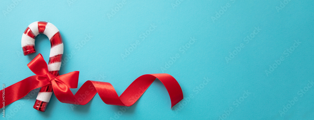 Fototapeta premium Christmas candy cane isolated on blue background. Merry Xmas greeting card template, space