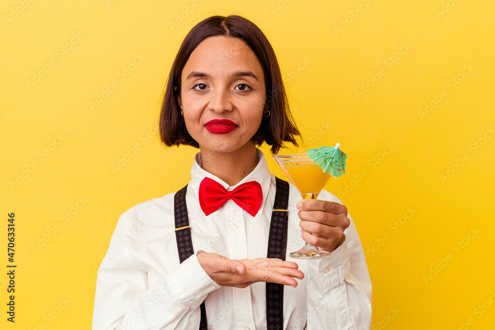 Young pretty bartender woman holding a cocktail on a yellow background Young pretty bartender woman holding a cocktail on a yellow background