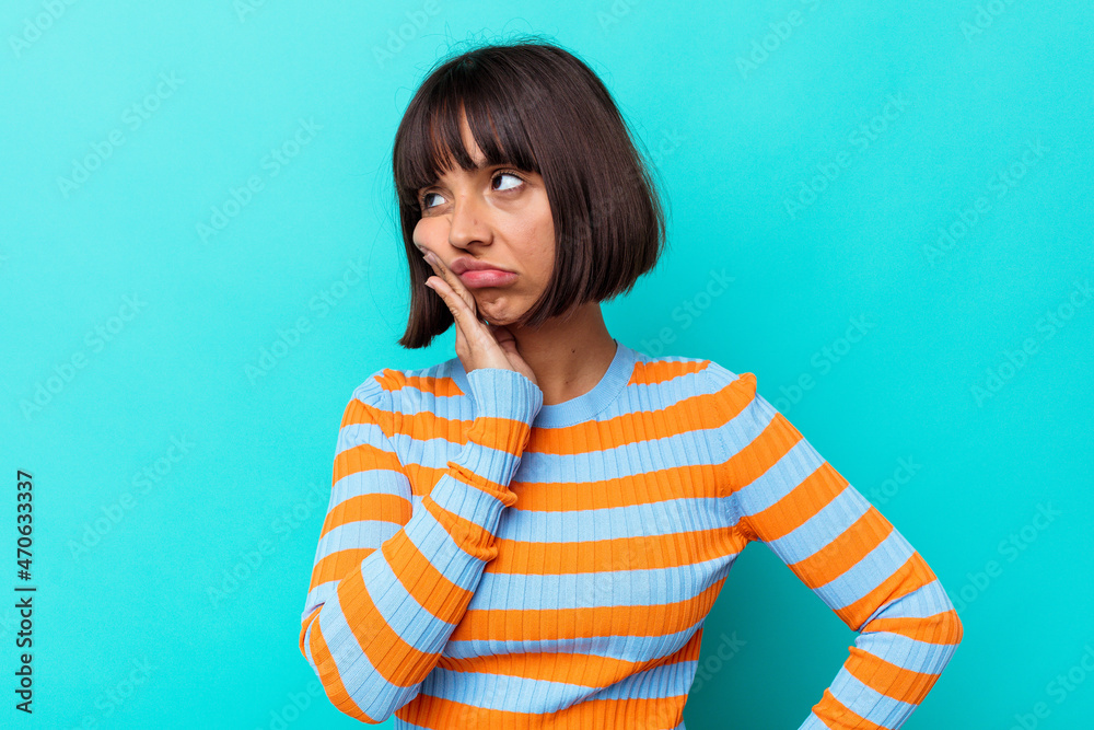 Young mixed race woman isolated on blue background who is bored, fatigued and need a relax day. Young mixed race woman isolated on blue background who is bored, fatigued and need a relax day.