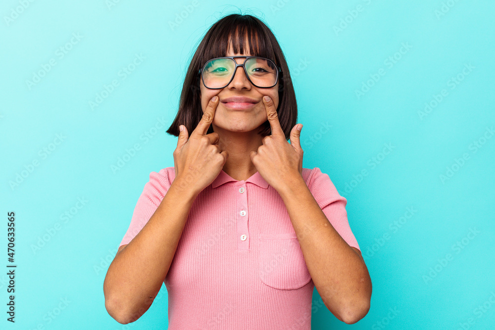Young mixed race woman isolated on blue background doubting between two options. Young mixed race woman isolated on blue background doubting between two options.