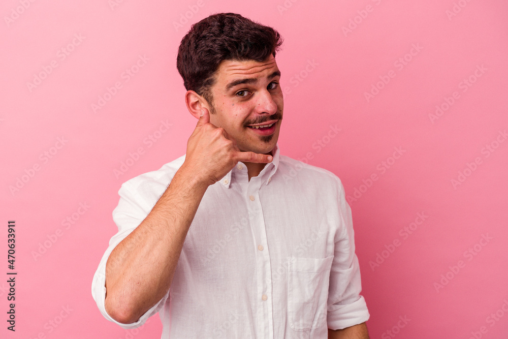 Young caucasian man isolated on pink background showing a mobile phone call gesture with fingers. Young caucasian man isolated on pink background showing a mobile phone call gesture with fingers.