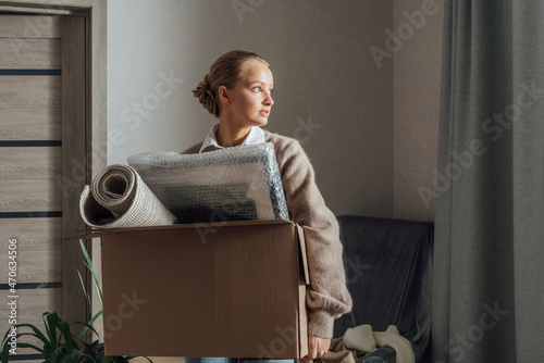 Woman with carton relocating in new apartment photo