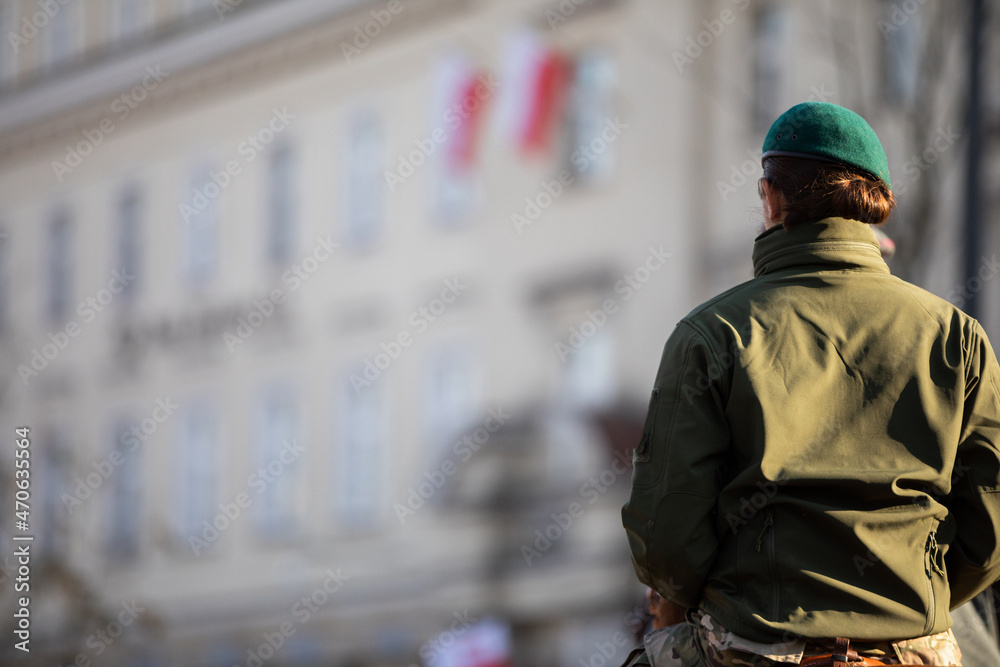 An army woman in uniform and green beret in the background of a building. An army woman in uniform and green beret in the background of a building.
