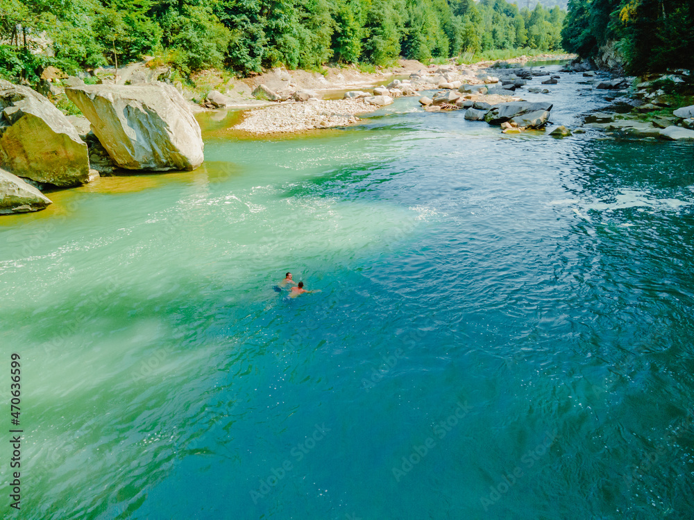 Obraz premium two men swimming in mountain river