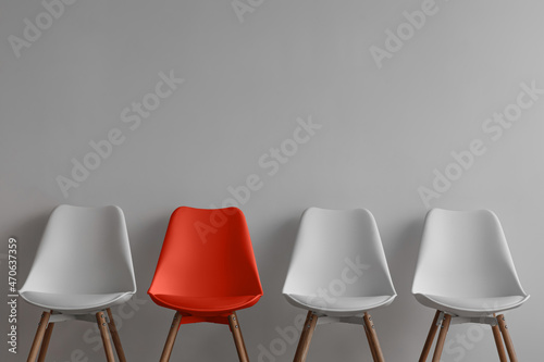 Three white chairs and red on gray wall background in office or room