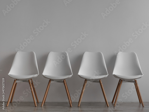 Schilderij op canvas Four vacant white chairs on gray wall background in office or living room