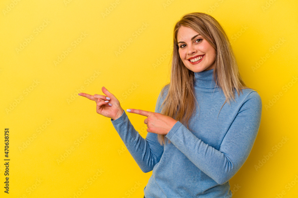 Young russian woman isolated on yellow background excited pointing with forefingers away. Young russian woman isolated on yellow background excited pointing with forefingers away.