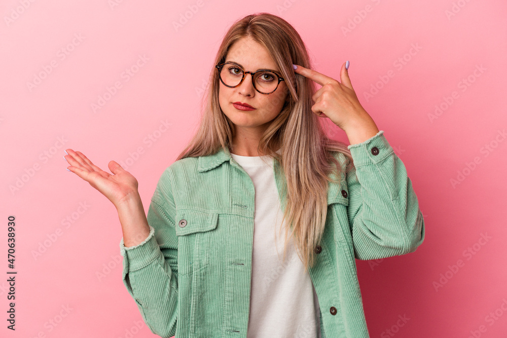Young russian woman isolated on pink background holding and showing a product on hand. Young russian woman isolated on pink background holding and showing a product on hand.
