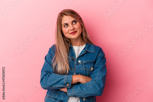 Young russian woman isolated on pink background dreaming of achieving goals and purposes