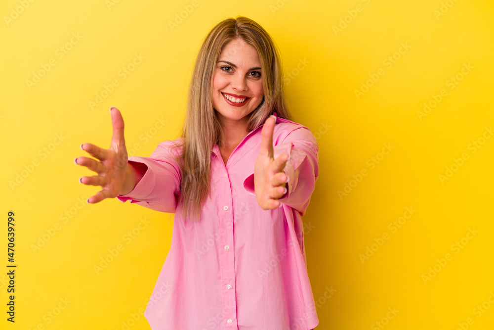 Young russian woman isolated on yellow background feels confident giving a hug to the camera.