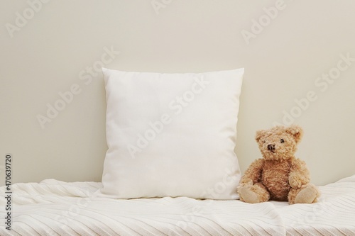 White square baby pillow mockup for design presentation, blank canvas nursery cushion, blanket and soft toy bear.