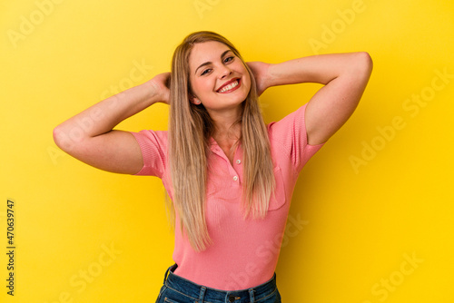 Young russian woman isolated on yellow background feeling confident, with hands behind the head.