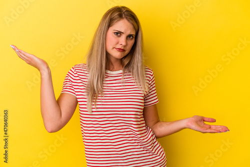 Young russian woman isolated on yellow background confused and doubtful shrugging shoulders to hold a copy space.