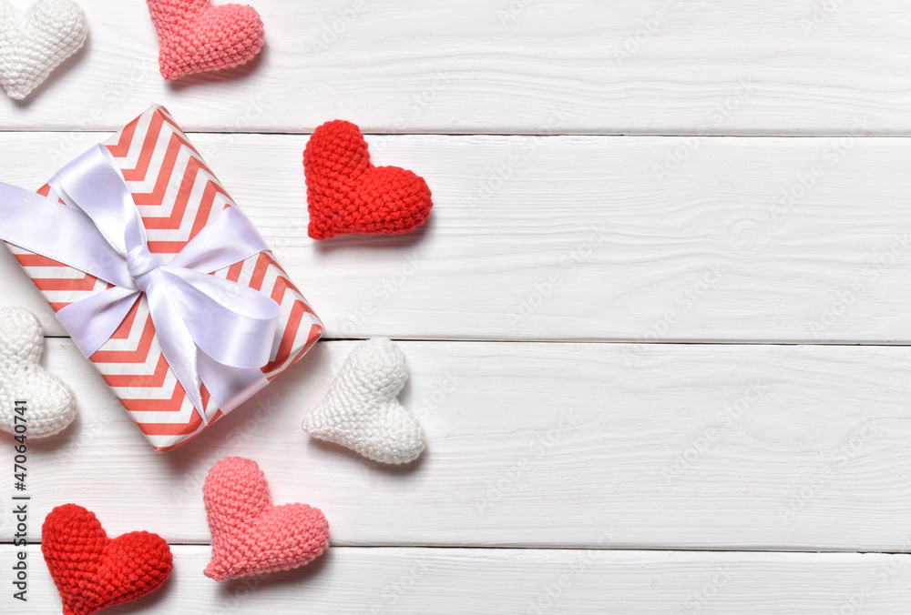 A banner for Valentine's Day with knitted hearts in a row on the right side on a white wooden background. February 14. A banner for Valentine's Day with knitted hearts in a row on the right side on a white wooden background. February 14.