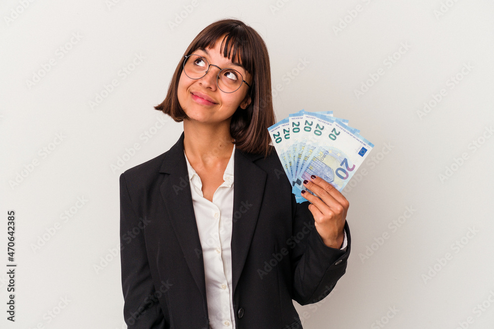 Young mixed race business woman holding a banknotes isolated on white background dreaming of achieving goals and purposes Young mixed race business woman holding a banknotes isolated on white background dreaming of achieving goals and purposes