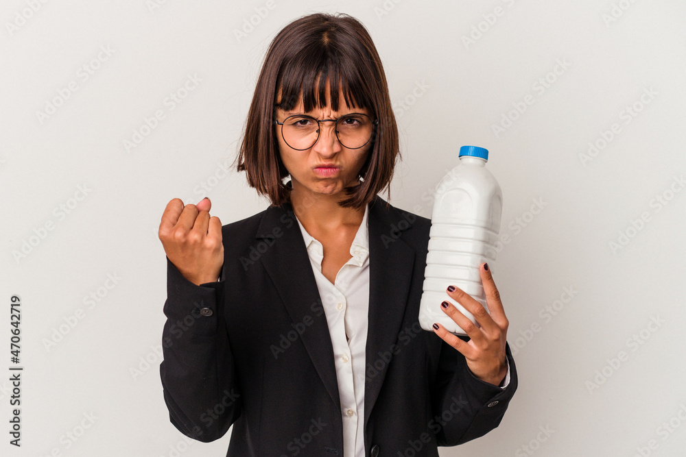 Young mixed race business woman holding a milk bottle isolated on white background showing fist to camera, aggressive facial expression. Young mixed race business woman holding a milk bottle isolated on white background showing fist to camera, aggressive facial expression.