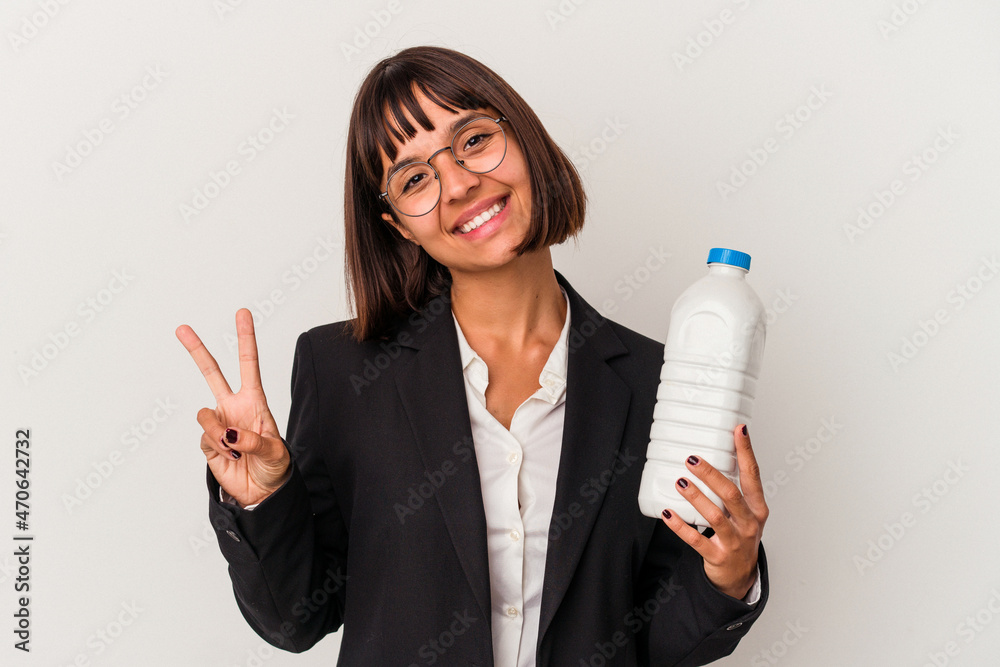 Young mixed race business woman holding a milk bottle isolated on white background joyful and carefree showing a peace symbol with fingers. Young mixed race business woman holding a milk bottle isolated on white background joyful and carefree showing a peace symbol with fingers.