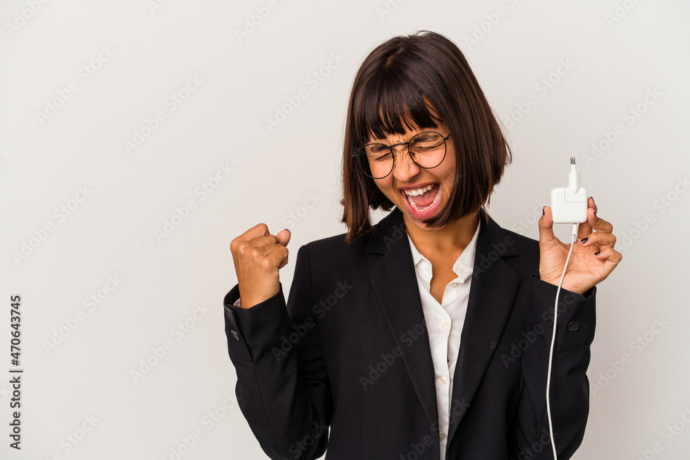 Young mixed race business woman holding a phone charger isolated on white background receiving a pleasant surprise, excited and raising hands. Young mixed race business woman holding a phone charger isolated on white background receiving a pleasant surprise, excited and raising hands.