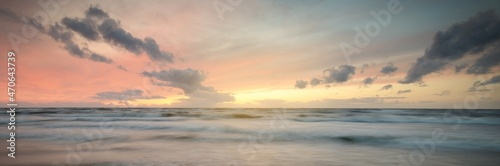 Baltic sea at sunset. Dramatic twilight sky, blue and pink glowing clouds, golden sunlight. Waves, splashing water. Picturesque scenery, seascape, cloudscape, nature. Panoramic view, long exposure