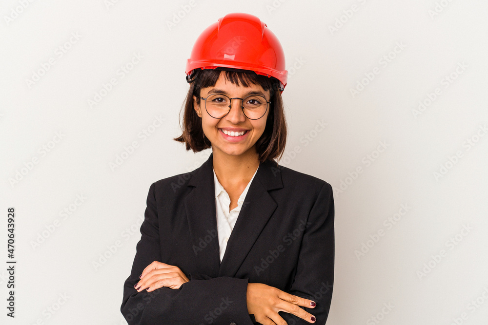 Young architect woman with red helmet isolated on white background who feels confident, crossing arms with determination. Young architect woman with red helmet isolated on white background who feels confident, crossing arms with determination.