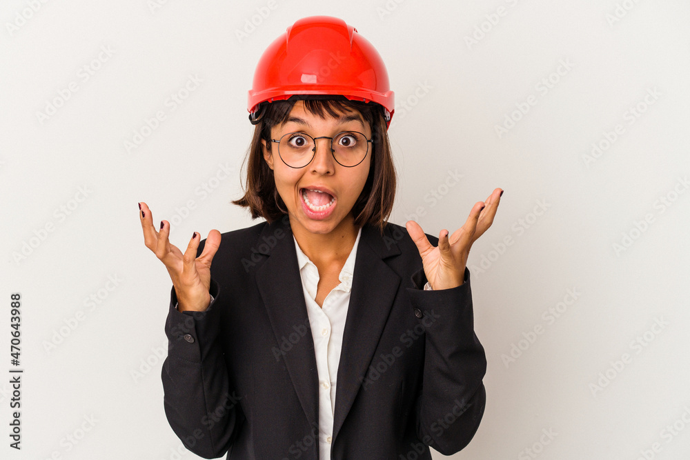 Young architect woman with red helmet isolated on white background celebrating a victory or success, he is surprised and shocked.