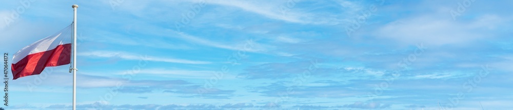 Against the background of blue sky and a few white clouds flies the national flag of Poland. Panorama. Against the background of blue sky and a few white clouds flies the national flag of Poland. Panorama.