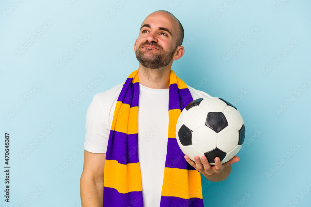 Young sport bald man wearing a scarf isolated on blue background  dreaming of achieving goals and purposes
