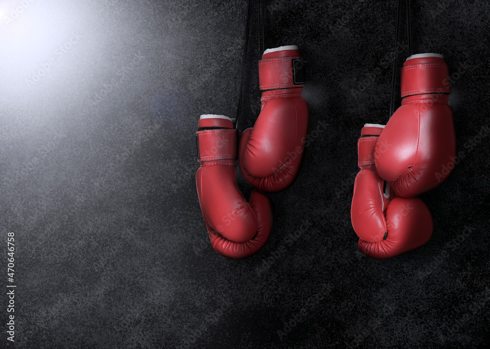 Two pairs of boxing gloves hanging against dark background