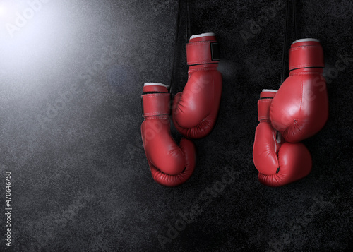 Two pairs of boxing gloves hanging against dark background