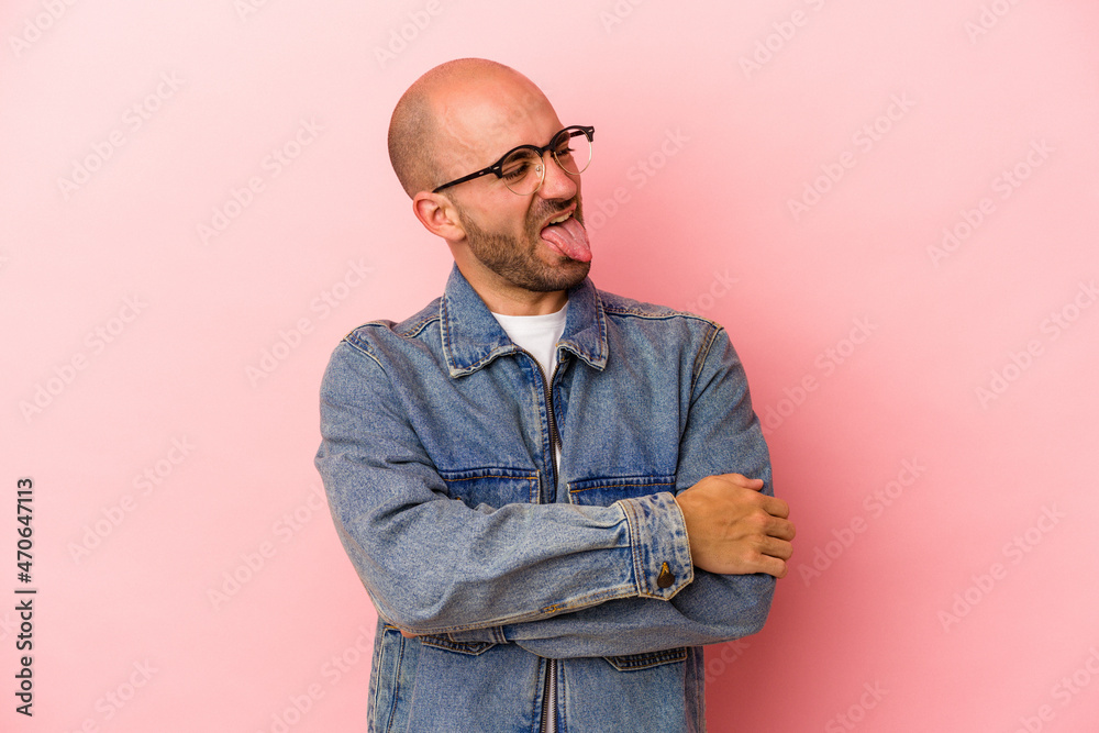 Fototapeta premium Young caucasian bald man isolated on pink background funny and friendly sticking out tongue.