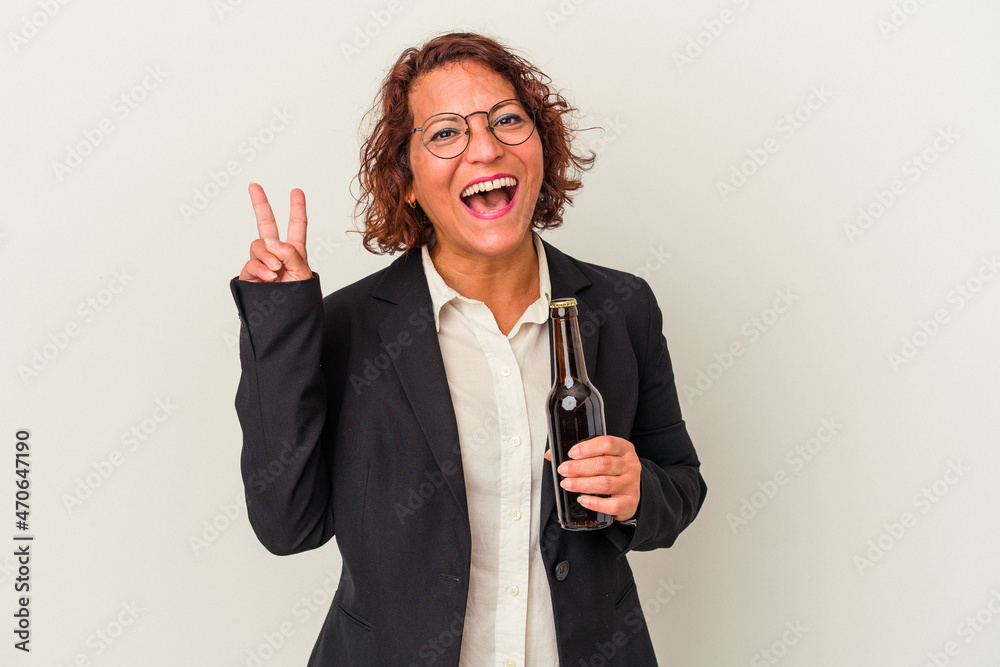 Middle age latin business woman holding a beer isolated on white background joyful and carefree showing a peace symbol with fingers. Middle age latin business woman holding a beer isolated on white background joyful and carefree showing a peace symbol with fingers.
