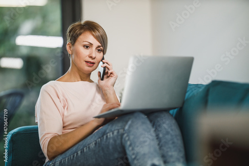 Woman Using Smartphone And Laptop While Working From Home Office
