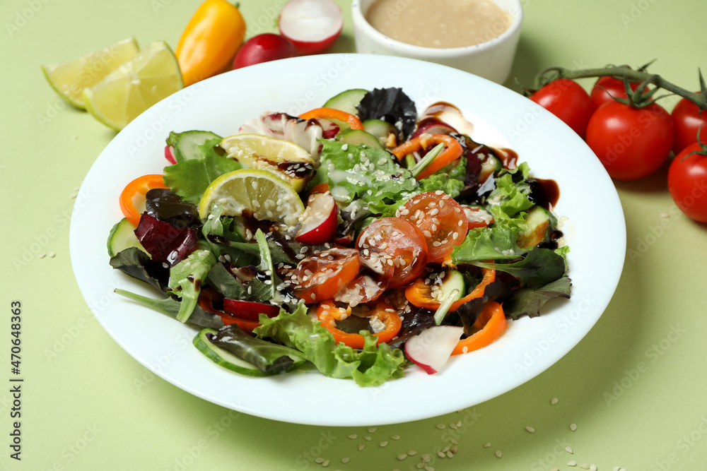 Concept of tasty food with vegetable salad with tahini sauce on green background Concept of tasty food with vegetable salad with tahini sauce on green background