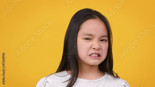Eww. Cute little asian girl frowning her face, expressing disgust and aversion, smelling or tasting something awful photo