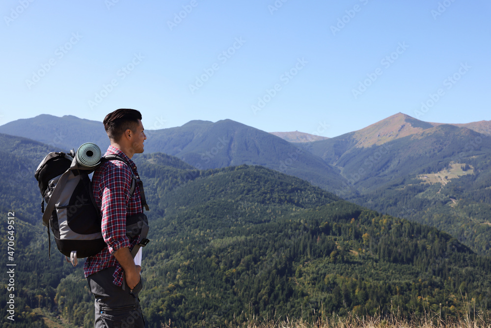 Tourist with backpack enjoying view in mountains on sunny day