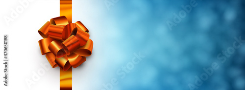 Orange foil ribbon with beautiful bow on blue blurred background.