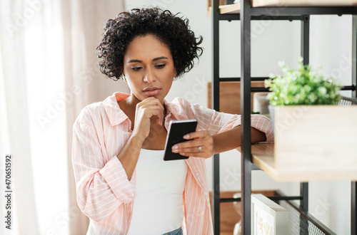 Obraz na płótnie technology and people concept - woman with smartphone standing at shelf at home