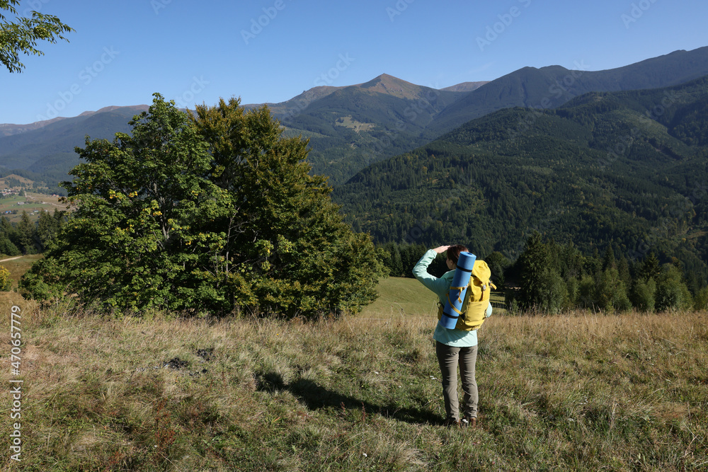 Obraz premium Tourist with backpack enjoying view in mountains on sunny day