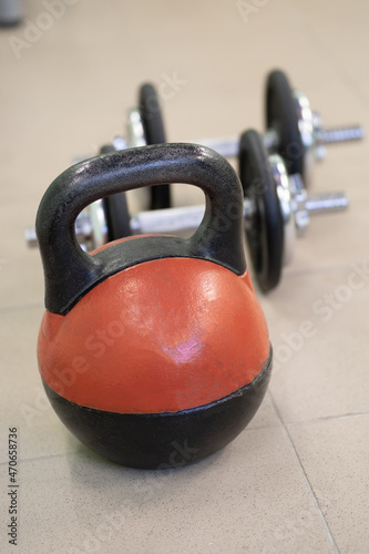 Sports equipment in the fitness club. Red kettlebell and dumbbells photo