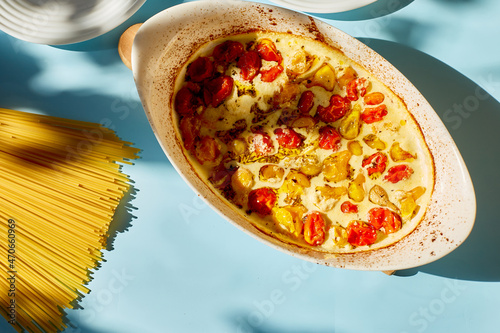 Trending viral recipe of baked tomatoes and feta with pasta on a blue background sunlight photo