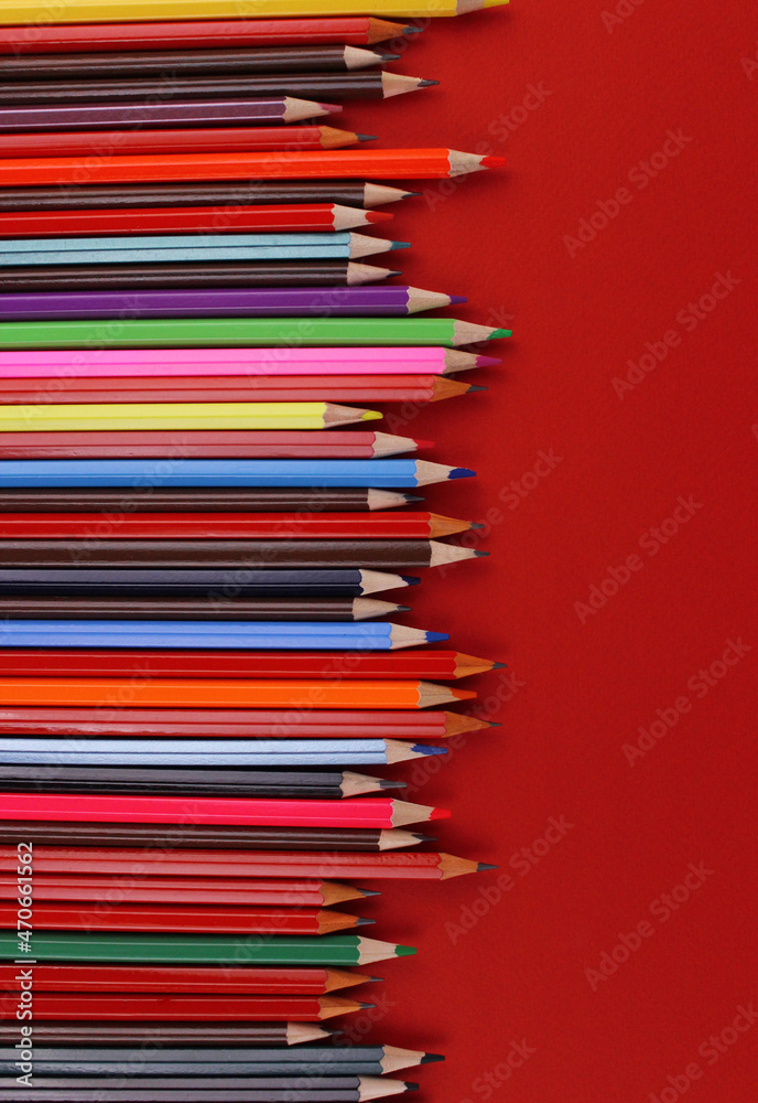 Wooden pencils of different colors on a red background Wooden pencils of different colors on a red background