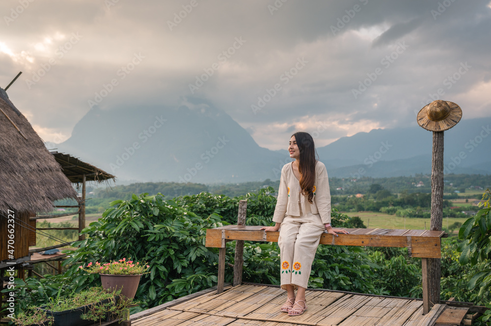 Young asian woman sitting on terrace and mountain view of Doi Luang Chiang Dao in the sunset