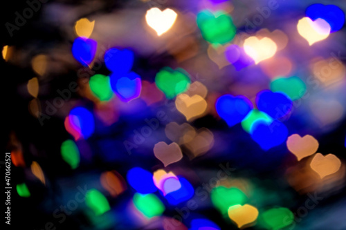 Blurred bright background, texture of multicolored lights in the shape of hearts