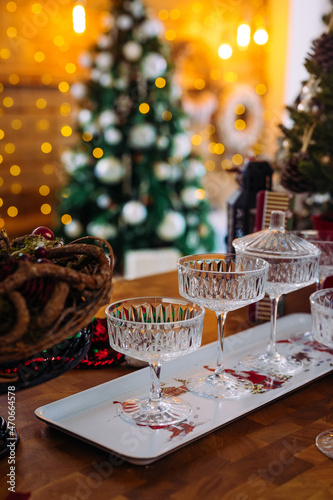 crystal glasses for sparkling wine on a white tray, Christmas tree on the background. The atmosphere of the New Year's celebration