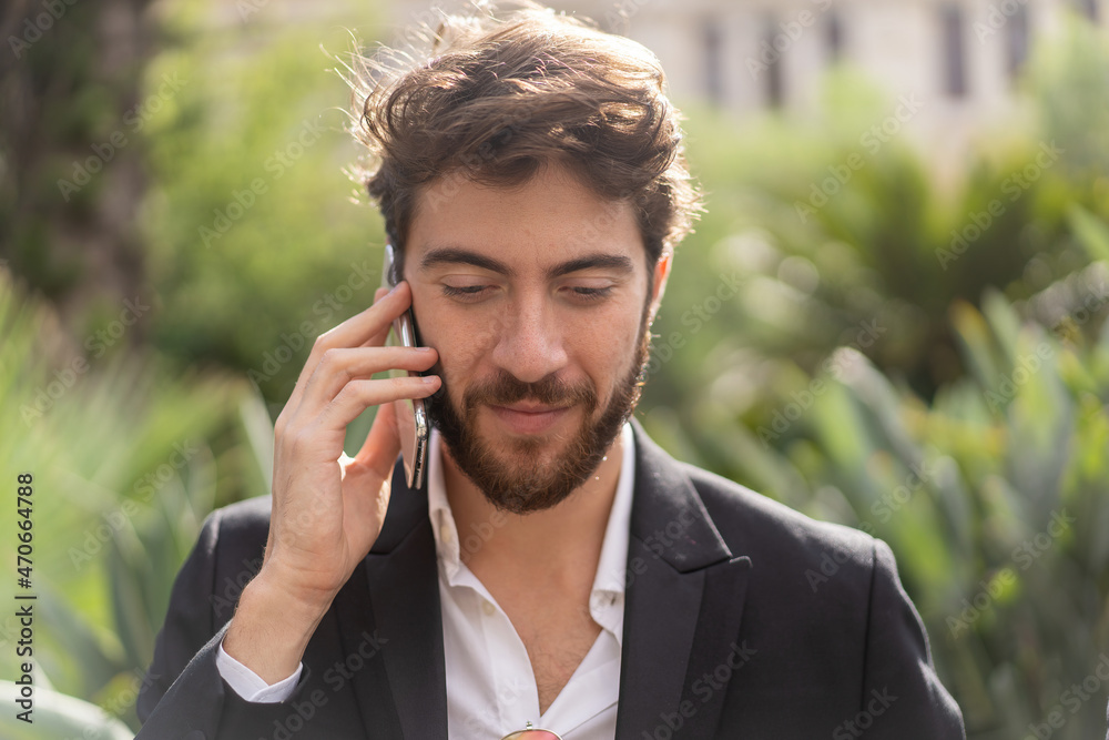 Young cheerful bearded guy in suit talking on the phone outdoors Young cheerful bearded guy in suit talking on the phone outdoors