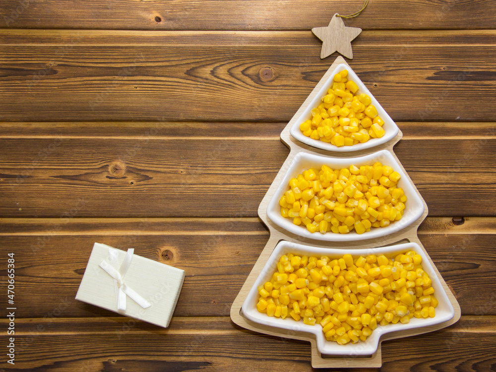 Happy New Year 2022. New Year's yellow corn in saucers in the form of a Christmas tree. Christmas wooden background with white numbers 2022