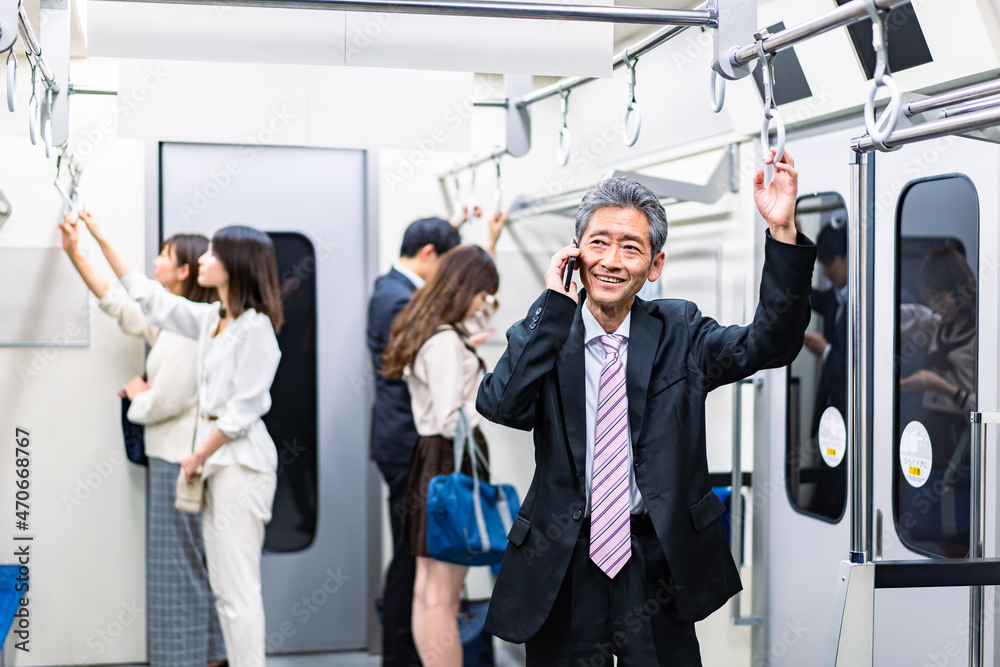 電車車内で通話をする中年ビジネスパーソン 電車車内で通話をする中年ビジネスパーソン