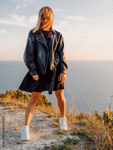 Beautiful woman in black dress posing outdoor with sunset.