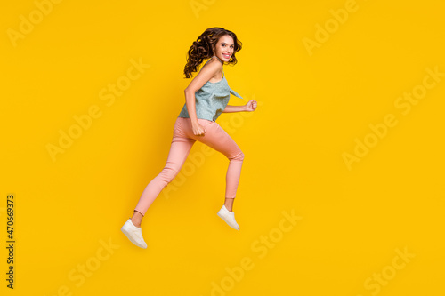 Full body photo of cheerful young woman jump up run empty space news isolated on yellow color background